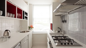 Una cocina moderna con armarios blancos, un lavamanos de acero inoxidable y una estufa a gas.