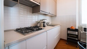 Et moderne køkken med hvide skabe, gasblus, vask og mikrobølgeovn.