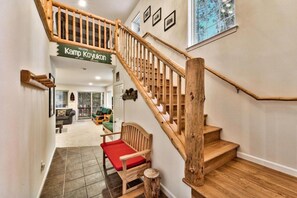 Una escalera de madera con un banco acolchado rojo al pie. Un cartel sobre las escaleras dice 'WELCOME TO Kamp Koyukon'.