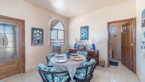 A dining area with a round table, chairs, and a window with blinds. - Cypress House close distance to the beach at Las Conchas (Puerto Peñasco)