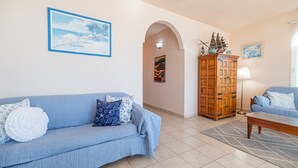 A living room with a blue sofa, a wooden cabinet, and a small table. - Cypress House close distance to the beach at Las Conchas (Puerto Peñasco)