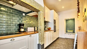 A modern kitchen with white cabinets, a green-tiled backsplash, and a wooden countertop. - Portas do Sol Terrace –pure charm in Alfama (A/C) (Lisbon)
