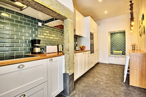 A modern kitchen with white cabinets, a green-tiled backsplash, and a wooden countertop. - Portas do Sol Terrace –pure charm in Alfama (A/C) (Lisbon)