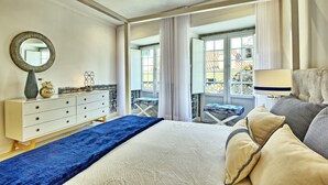 A bedroom with a bed, a dresser, a mirror, a window, and a balcony. - Portas do Sol Terrace –pure charm in Alfama (A/C) (Lisbon)