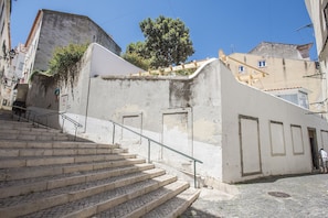 A set of stone steps leading up to a white building with a small door and a window. - Portas do Sol Terrace –pure charm in Alfama (A/C) (Lisbon)