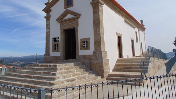 Una pequeña iglesia con fachada blanca, escalones de piedra que conducen a la entrada y un tejado de tejas rojas.