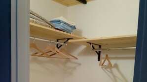 Un vestidor con estantes de madera, una barra para colgar ropa y un banco.
