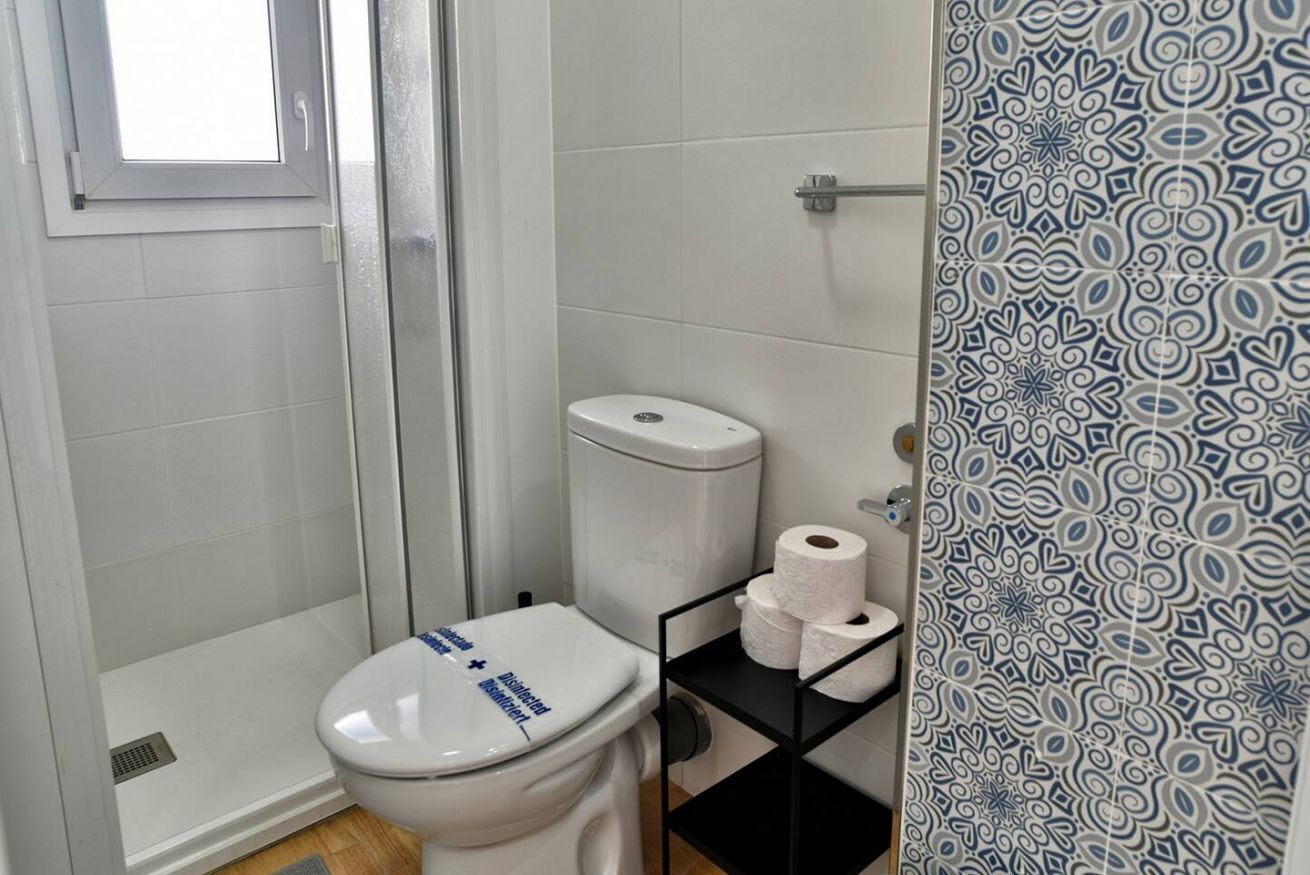 A bathroom with a toilet, a shower, and a patterned wall.