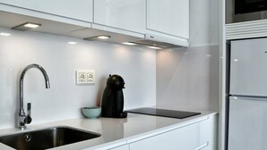 Una cocina moderna con un lavamanos de acero inoxidable, una cafetera negra y un refrigerador blanco.