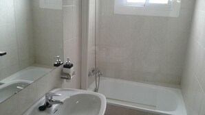 Un baño con bañera, lavabo y ducha.