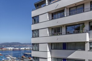 Un edificio de varios pisos con balcones que dan a un puerto deportivo.