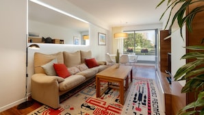 Ein modernes Wohnzimmer mit Sofa, Couchtisch und einem großen Fenster.