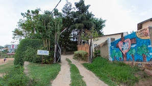 A dirt path leading to a building with a sign reading "GOLF EDEG GUEST HOUSE". - Golf Eden Guest House (Kigali)