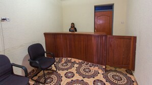 A room with a wooden reception desk, a patterned carpet, and a black office chair. - Medi Motel (Kigali)