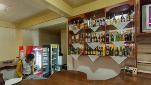 A bar area with a wooden counter and shelves stocked with various liquor bottles. - Medi Motel (Kigali)
