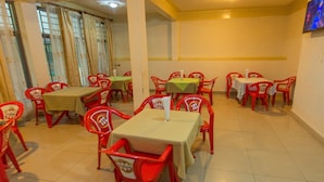 A dining area with red chairs and tables, some with green tablecloths. - Medi Motel (Kigali)