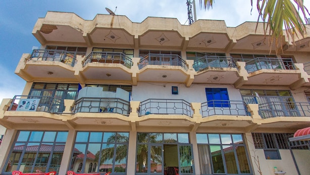 A multi-story building with balconies, large windows, and outdoor seating. - Medi Motel (Kigali)