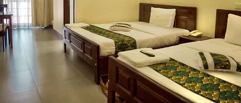 Two single beds with wooden headboards, a bedside table, a fan, and a window with curtains.