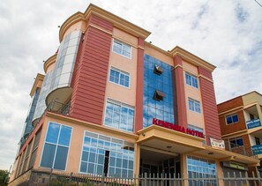 A multi-story hotel with a prominent red and beige facade, large windows, and a visible entrance.