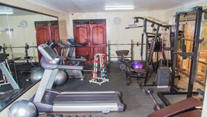 A gym with exercise equipment, a treadmill, dumbbells, and a weight bench. - Kenendia Hotel (Kampala)
