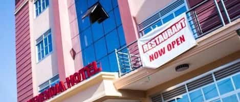 A hotel with a prominent sign indicating a restaurant is now open.