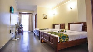 A hotel room with a bed, bedside table, and a desk with a chair. - Kenendia Hotel (Kampala)