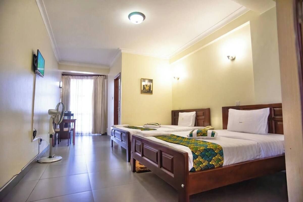 A hotel room with a bed, bedside table, and a desk with a chair.