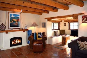 Uma sala de estar aconchegante com lareira, vigas de madeira e assentos confortáveis.