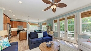 A spacious living area with a kitchen, a dining area, and a balcony with large windows.
