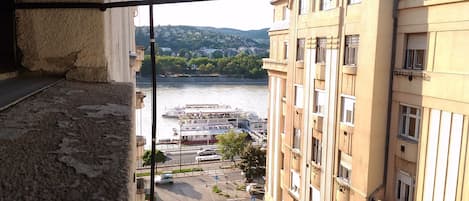 A view from a balcony overlooking a river with boats, a bridge, and buildings.