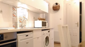 A compact kitchen with a dishwasher, microwave, and washing machine. - elite suite, old town, fast wifi, central heating (Budapest)