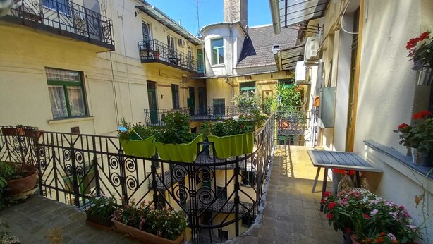 A courtyard with potted plants, a small table, and a staircase leading to a balcony. - elite suite, old town, fast wifi, central heating (Budapest)
