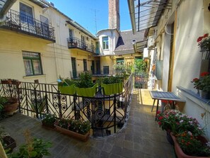 A courtyard with potted plants, a small table, and a staircase leading to a balcony. - elite suite, old town, fast wifi, central heating (Budapest)