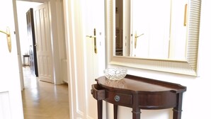 A hallway with a wooden console table, a crystal bowl, and a mirror with a decorative frame. - elite suite, old town, fast wifi, central heating (Budapest)