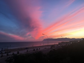 Una spiaggia con un cielo al tramonto, lampioni e un ristorante di pizza.
