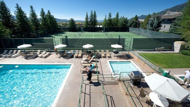 A pool area with a tennis court, lounge chairs, and umbrellas. - JHRL - Tensleep A2 - First floor condominium located in Teton Village (Teton Village)