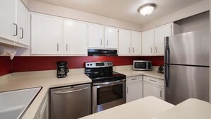A modern kitchen with white cabinets, stainless steel appliances, a red backsplash, and a built-in oven. - JHRL - Tensleep A2 - First floor condominium located in Teton Village (Teton Village)
