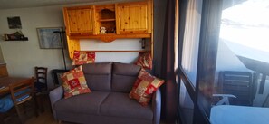 Ein gemütliches Interieur mit einer Couch, Holzschränken, einem Esstisch und einem Fenster mit Blick.