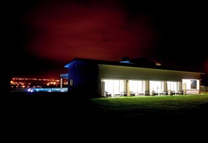 A building with a large open patio area, a covered outdoor seating area, and a well-lit facade. - Martin Guest House AZORES (Terceira Island) Dream destination (PRAIA DA VITORIA)