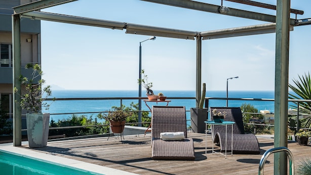A poolside area with lounge chairs and potted plants, overlooking a clear view of the sea. - Artistic Private Pool Villa with Gorgeous Gardens (Chania)