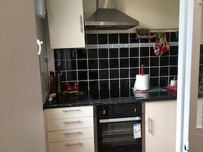Cocina con salpicadero de azulejos negros, electrodomésticos de acero inoxidable y horno pequeño.