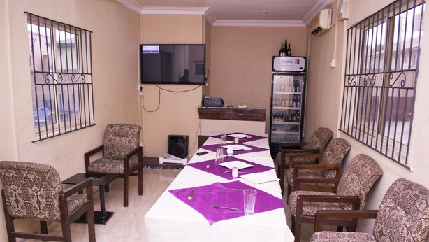 A conference room with a long table, patterned chairs, a television, and a refrigerator. - Maxton Suites Magodo (Lagos)