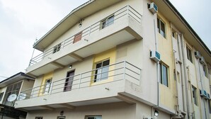Un edificio de varios pisos con balcones, unidades de aire acondicionado y una antena parabólica.