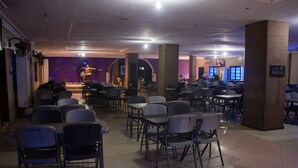 A spacious indoor dining area with multiple tables and chairs, a stage with a performer, and a 'No Smoking' sign. - Emota Paradise Phase 2 (Lagos)