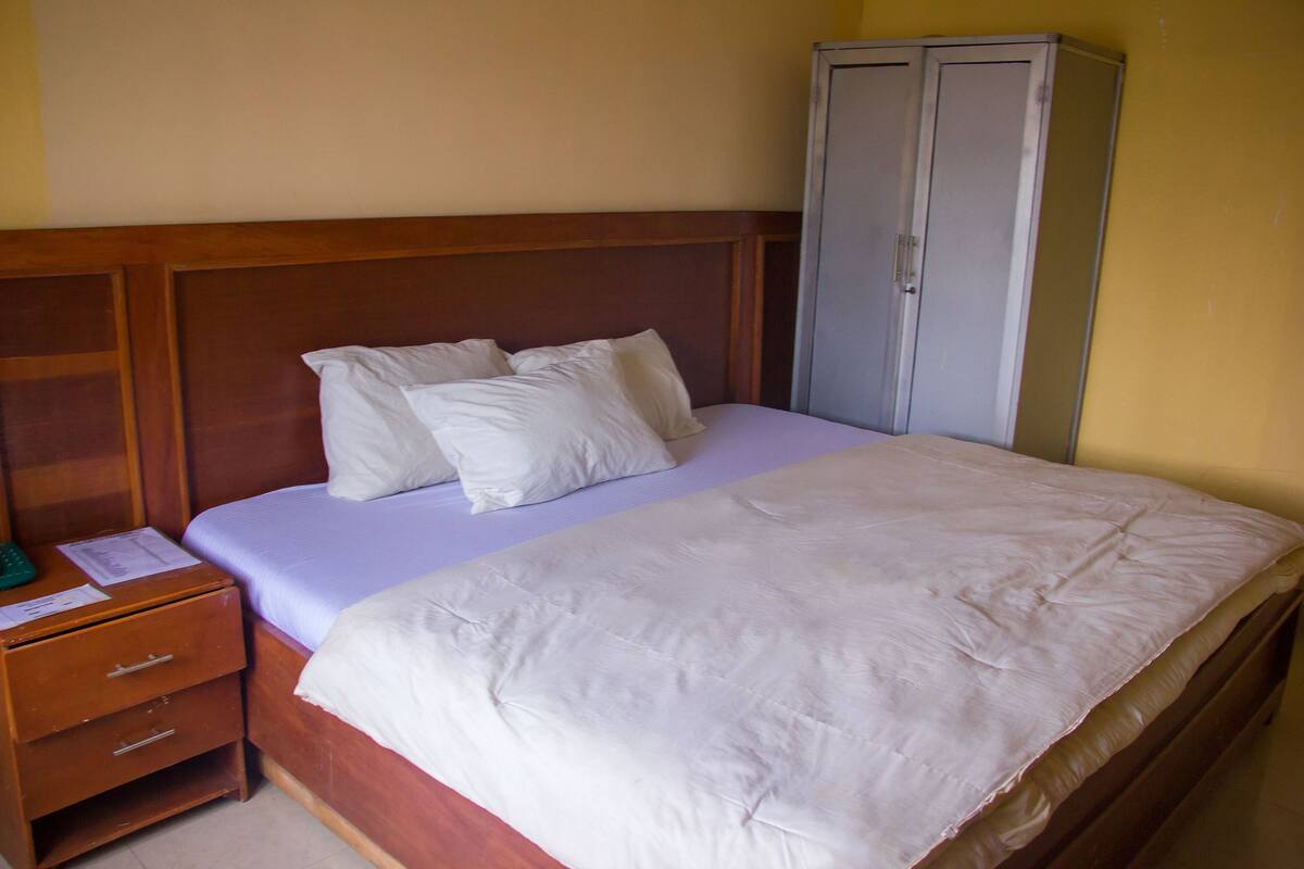 A single bed with a wooden headboard, a nightstand with drawers, and a wardrobe.