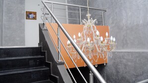 A staircase with a chandelier, a framed picture on the wall, and a marble wall. - Kings Celia Hotel & Suites (Lagos)