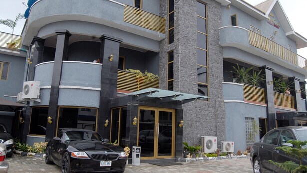 A multi-story hotel with a modern design, featuring balconies, a central entrance with glass doors, and air conditioning units. - Kings Celia Hotel & Suites (Lagos)