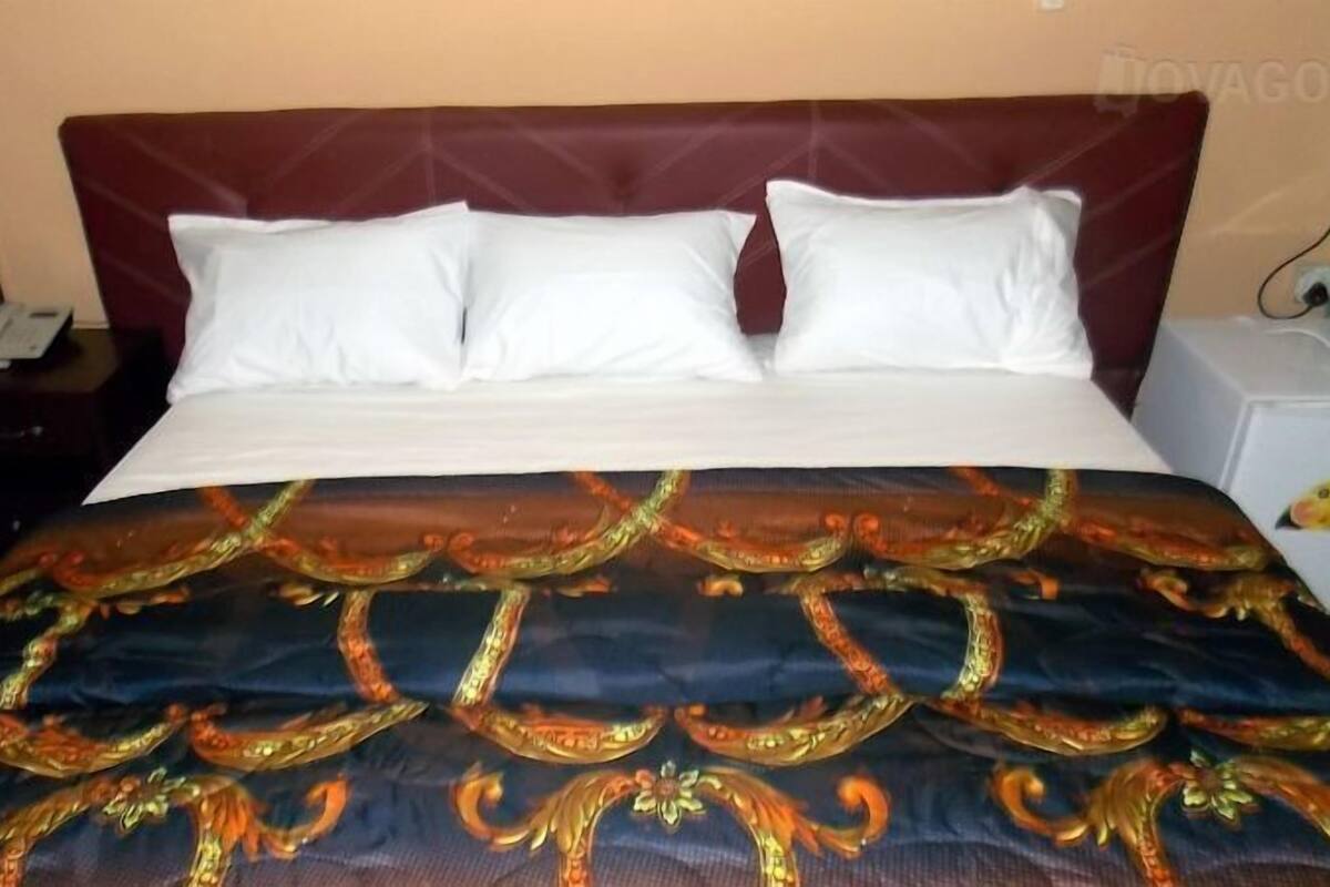 Ein Bett mit weißen Kissen und einer gemusterten Tagesdecke.