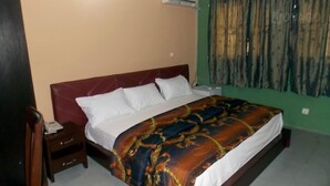 A bedroom with a bed, a nightstand, and a green wall. - SureRest Hotel & Suites (Lagos)