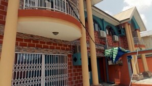 A multi-story building with a balcony, a security camera, and a gated entrance. - SureRest Hotel & Suites (Lagos)